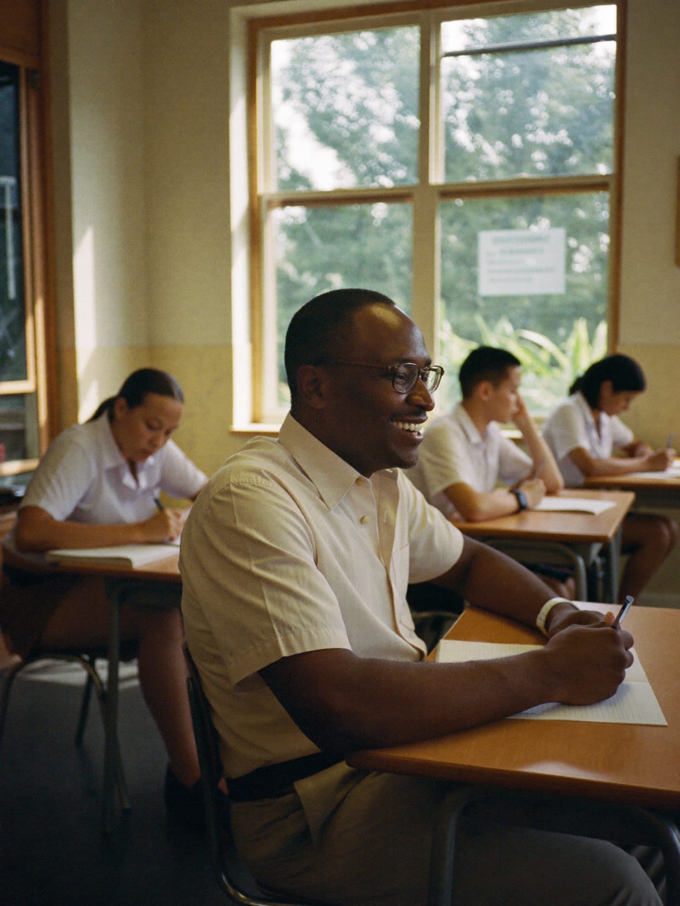Teacher walking between desks in a bright classroom while students work in small groups