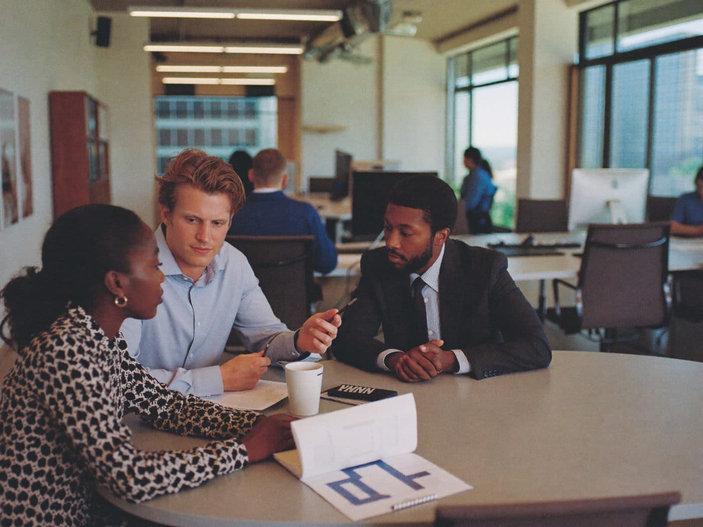 Finance team of three discussing a printed report around a table