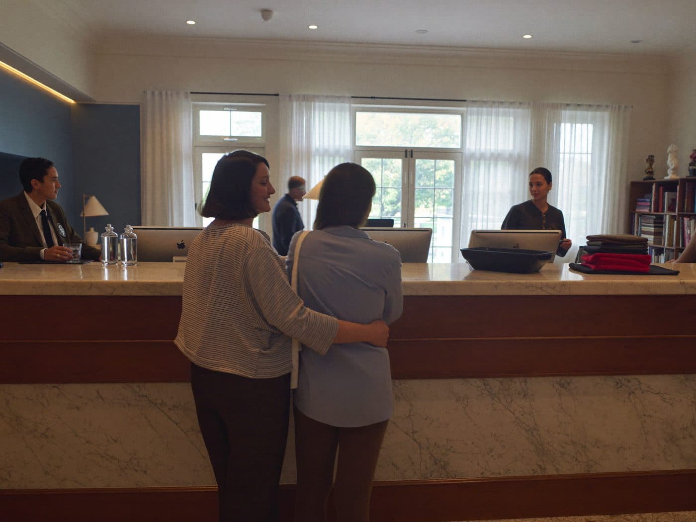 Hotel receptionist welcoming a guest at the front desk of a hotel lobby