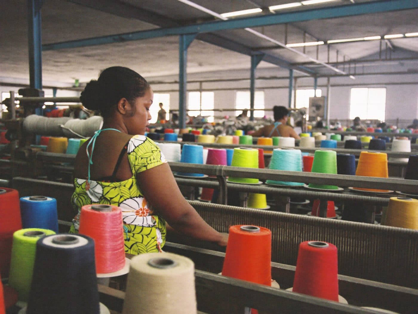 Worker tending a textile loom on a factory floor
