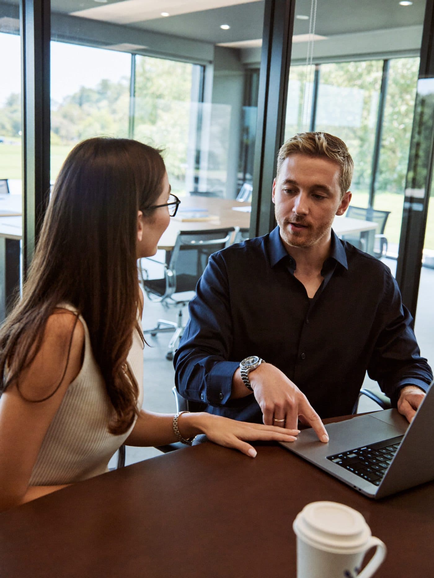 Two consultants talking through a document in a glass-walled meeting room